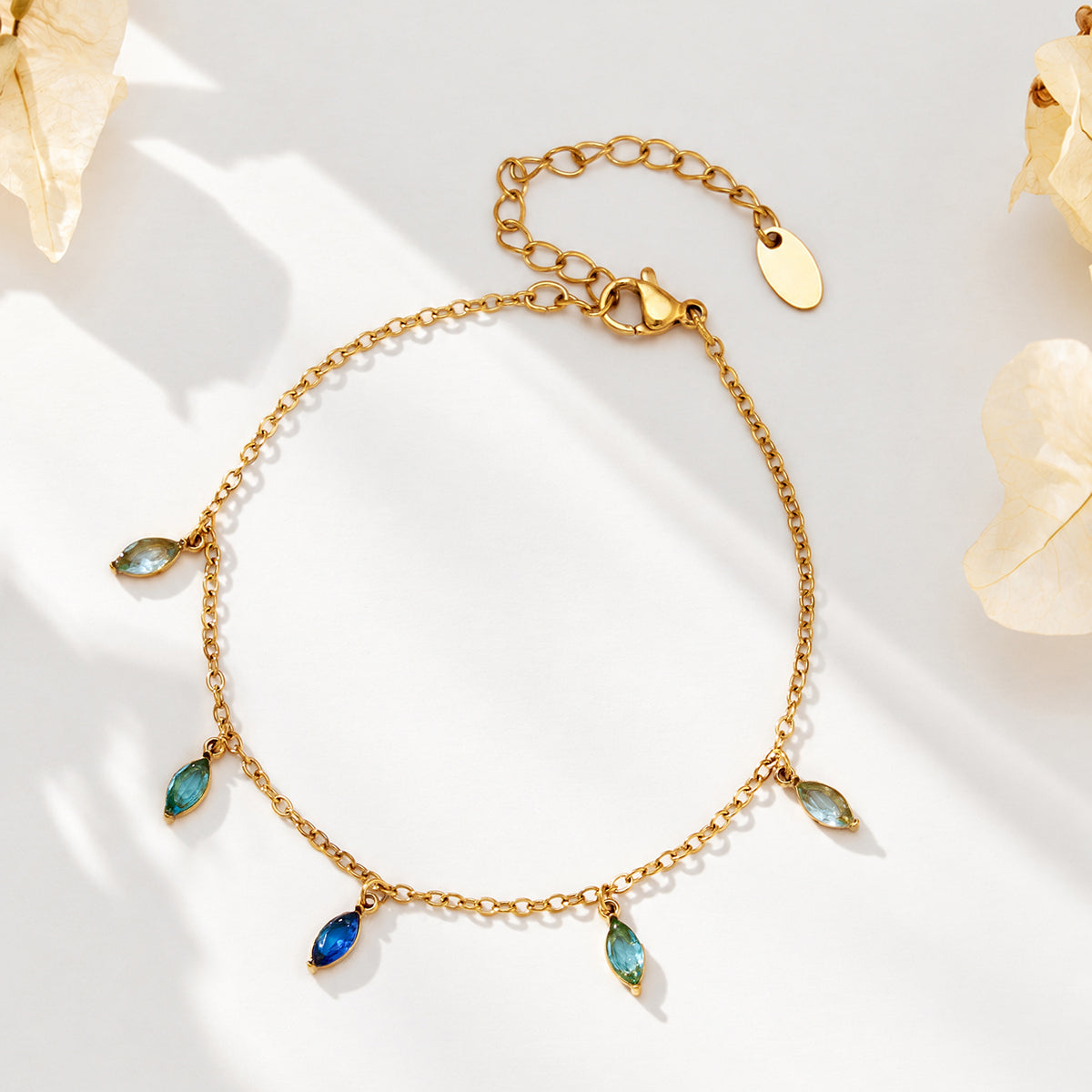 Gold-tone chain bracelet with blue and green pointed teardrop charms arranged in a circular shape.