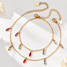 Two gold-tone fine-chain jewelry pieces with colorful teardrop charms and extension chains on a light surface.
