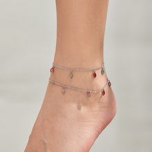 Steel-tone fine-chain anklets with colorful dangling teardrop charms worn around an ankle.