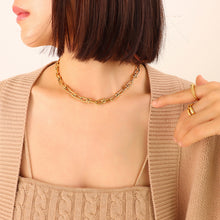 Model wearing a gold U-link chain necklace with a minimalist outfit