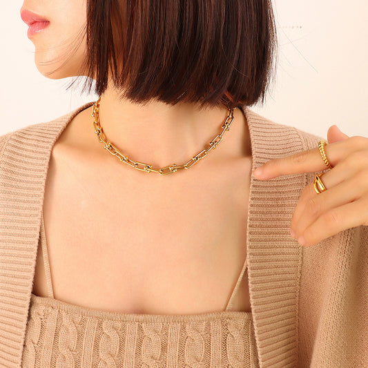 Model wearing a gold U-link chain necklace with a minimalist outfit