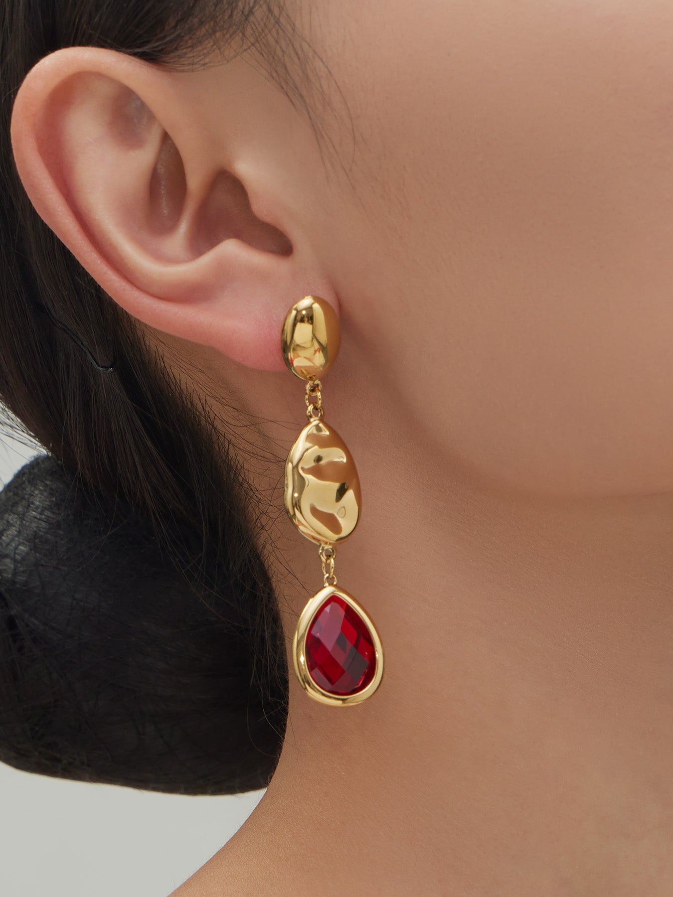 Side profile of model wearing 18K gold plated ruby red water drop hypoallergenic earrings for sensitive ears.