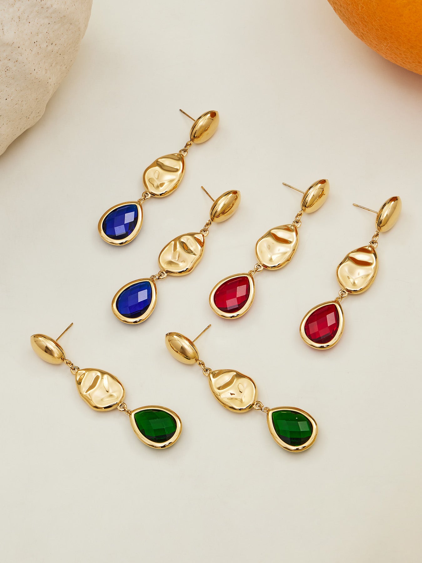 Flat lay of tarnish-free 18K gold plated stainless steel Czech glass pendant earrings for jewelry wholesale.