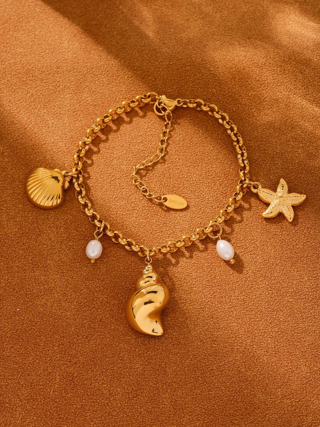 Warm towel flat lay of freshwater pearl shell charm bracelet, waterproof tarnish-free coastal jewelry for wholesale boutiques