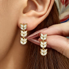 Close-up model view of wheat motif CZ drop earrings with layered leaf design