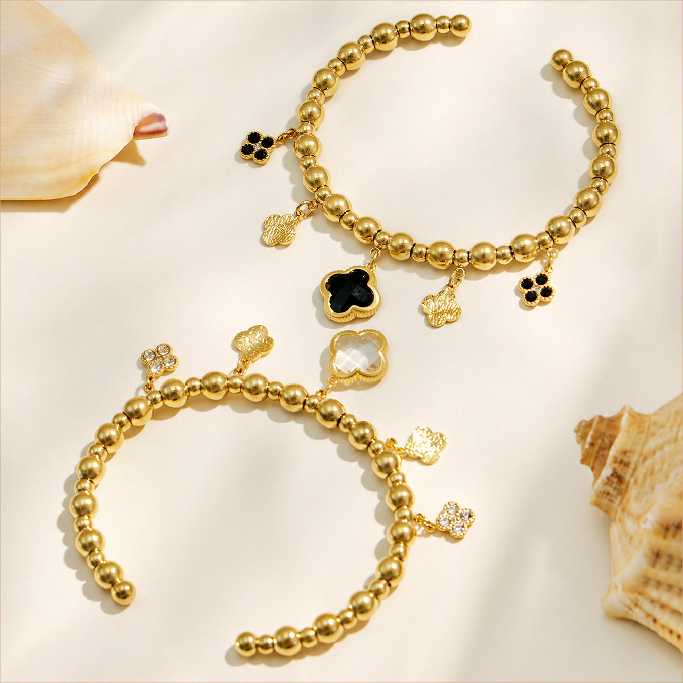 White and black four-leaf clover bracelets displayed in a neutral flat lay
