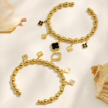 White and black four-leaf clover bracelets displayed in a neutral flat lay