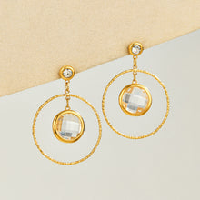 White glass stone drop earrings displayed with twisted gold-tone hoops