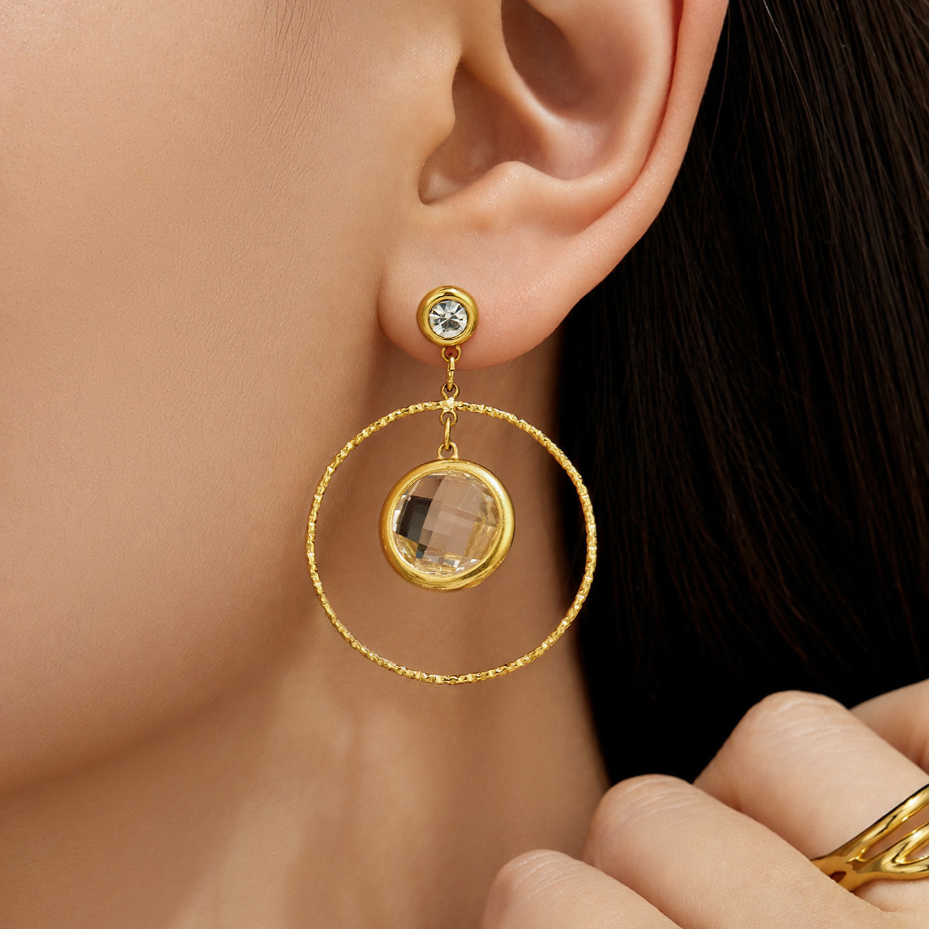 Model wearing white glass stone drop earrings with a gold circular frame