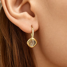 Model wearing white glass stone drop earrings with gold-tone setting