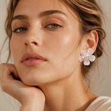 White pearl flower stud earrings worn on ear close up
