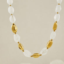 White organic resin bead necklace with sculptural gold stainless steel accents on a clean background