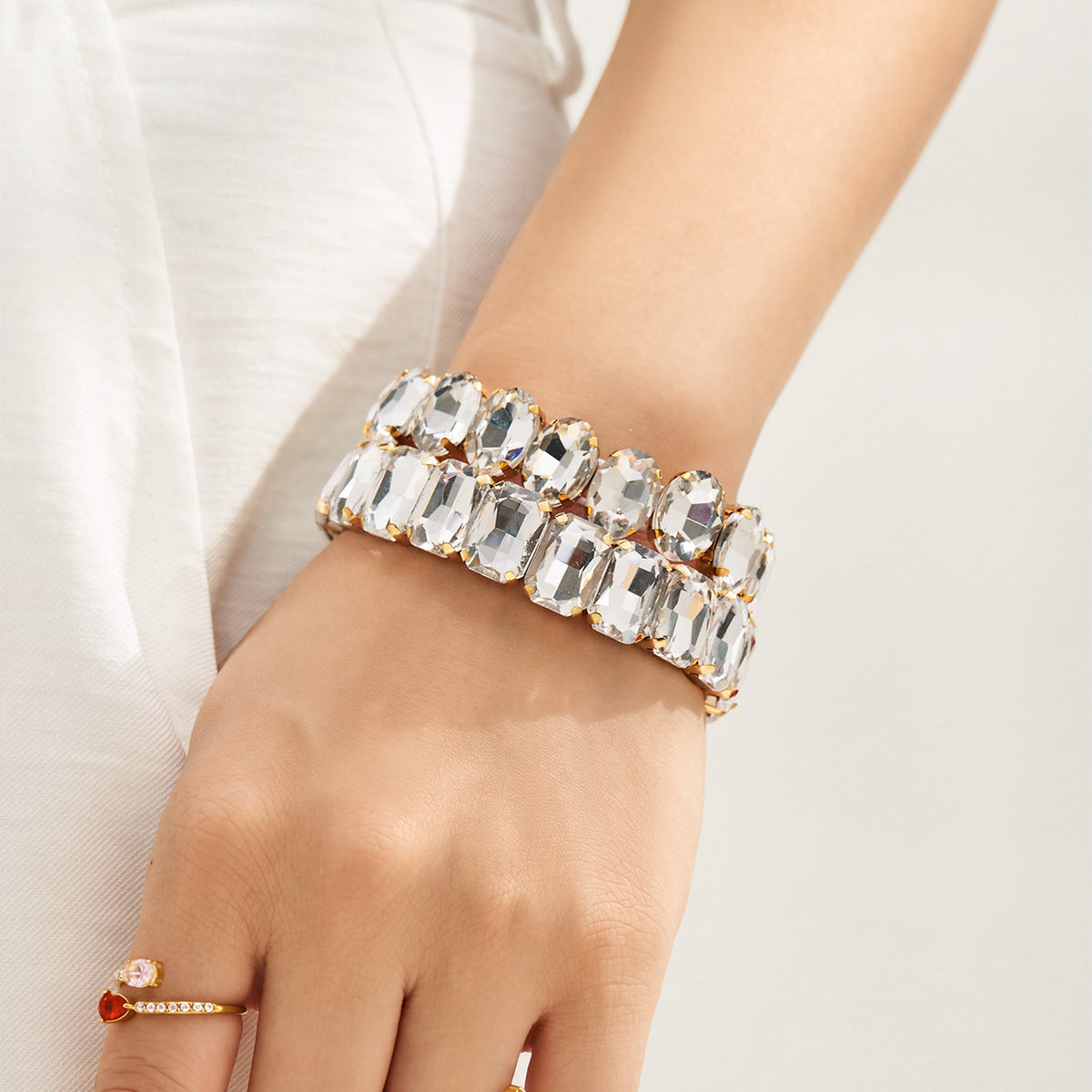 Wide gold rhinestone stretch bracelet with clear faceted glass stones worn on wrist