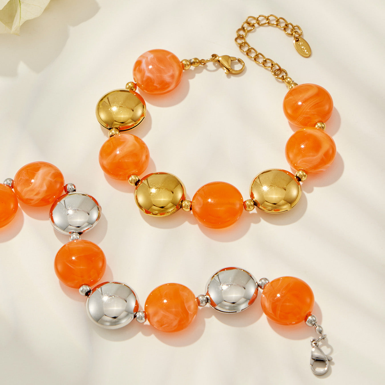 Close-up of yellow-orange resin bead bracelets with gold- and steel-tone accents on a clean product background.