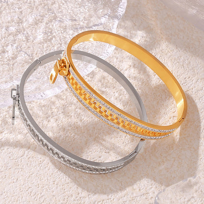 18k pvd gold and stainless steel zipper rhinestone bangle, displayed on textured surface