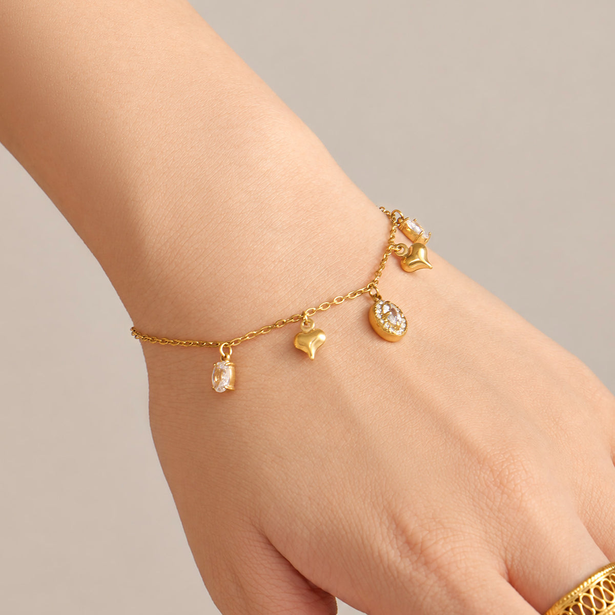 Close-up of gold zircon charm bracelet with delicate dangling stone details on wrist