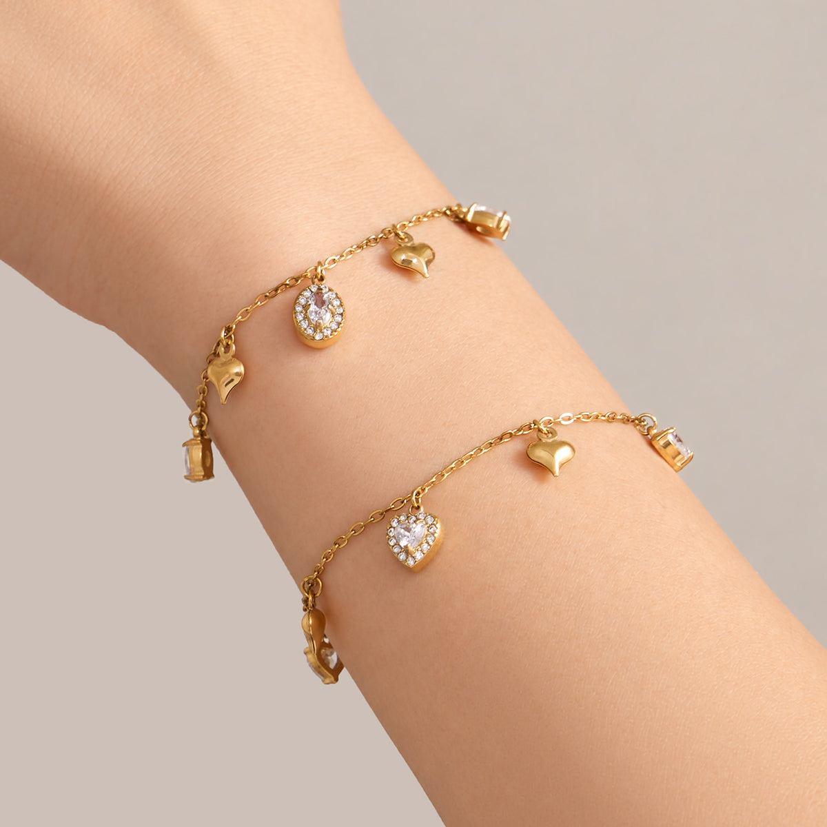 Gold zircon charm bracelets with spaced stone drops worn on wrist