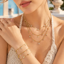 Model wearing matching zircon charm necklace and bracelet collection in 316L stainless steel gold tone