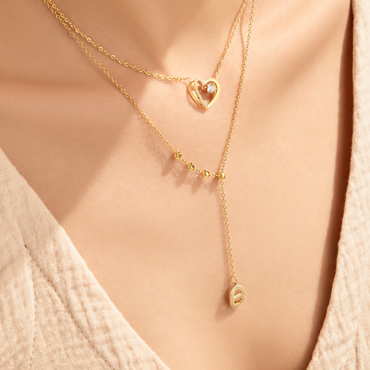 Close-up of layered zircon heart pendant and Y necklaces worn on model