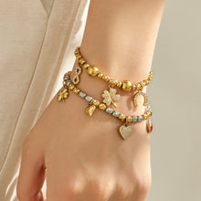 Gold multi charm bracelets layered on the wrist with mixed symbolic pendant details