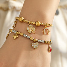Mixed charm bracelets in gold and steel finishes worn together with zircon and pendant details