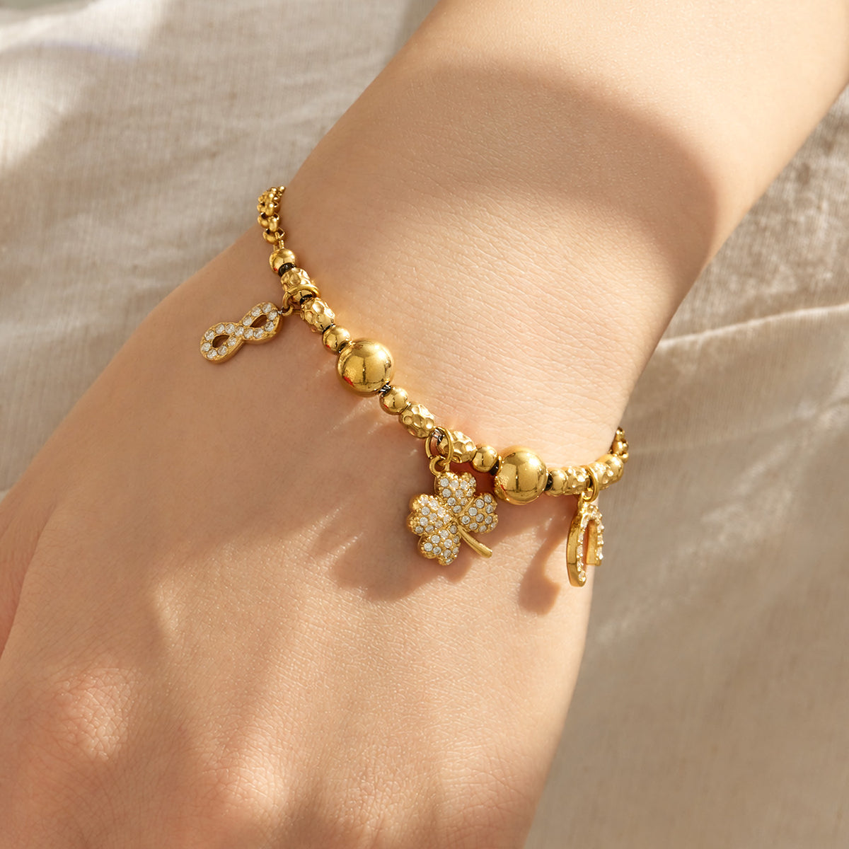 Gold multi charm bracelet with small decorative pendants and zircon accents worn on the wrist