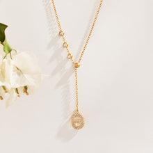 Gold-tone zircon Y drop necklace with round stone accents displayed with white flowers
